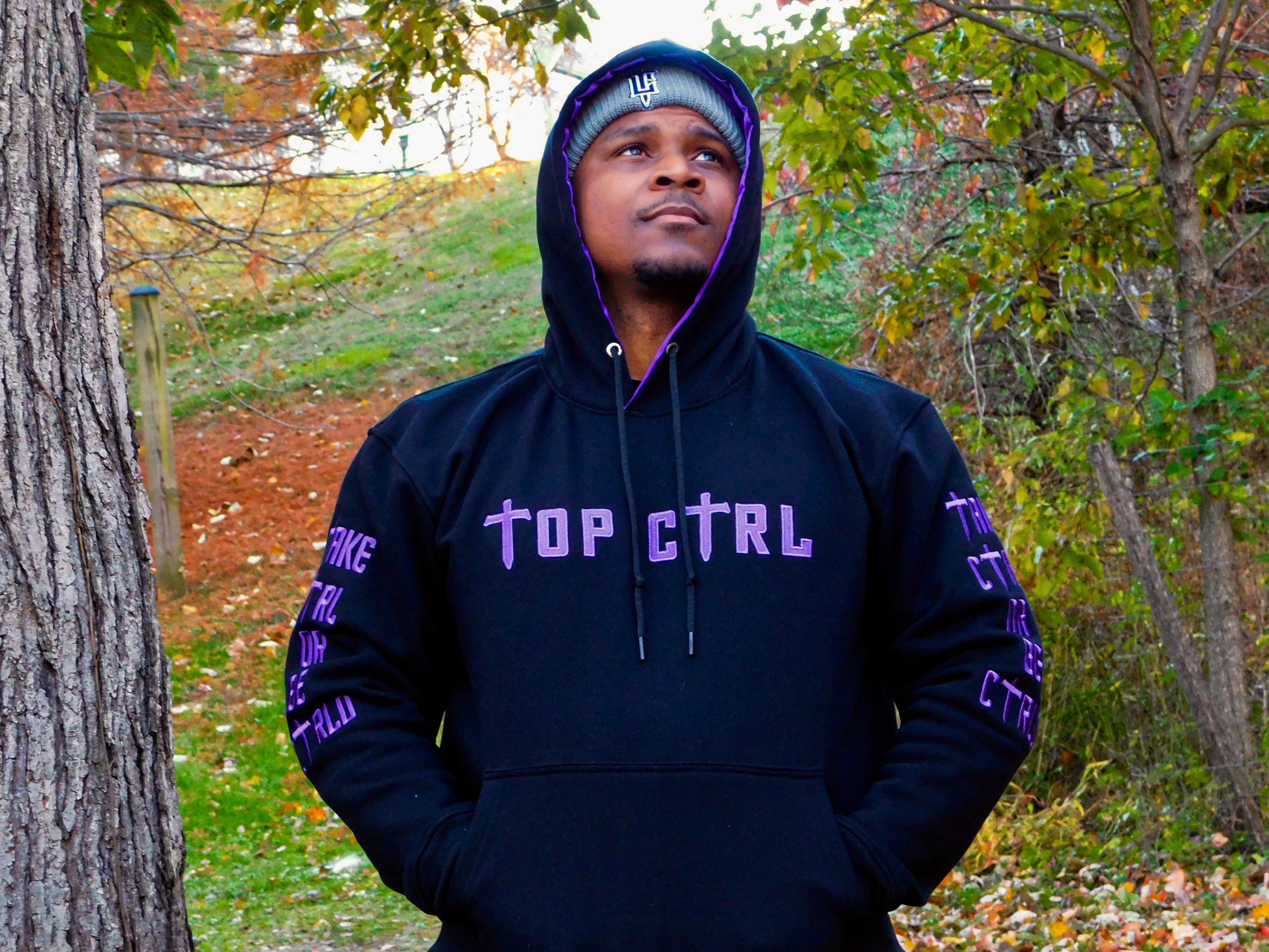 Person wearing a black and purple hoodie with 'TOP CTRL' text outdoors.